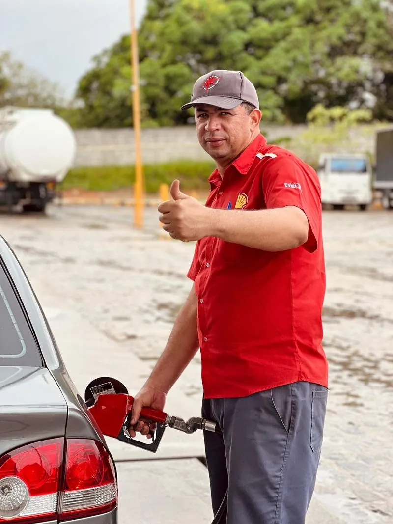 Frentista do Posto Caju abastecendo um carro, com o polegar para cima.