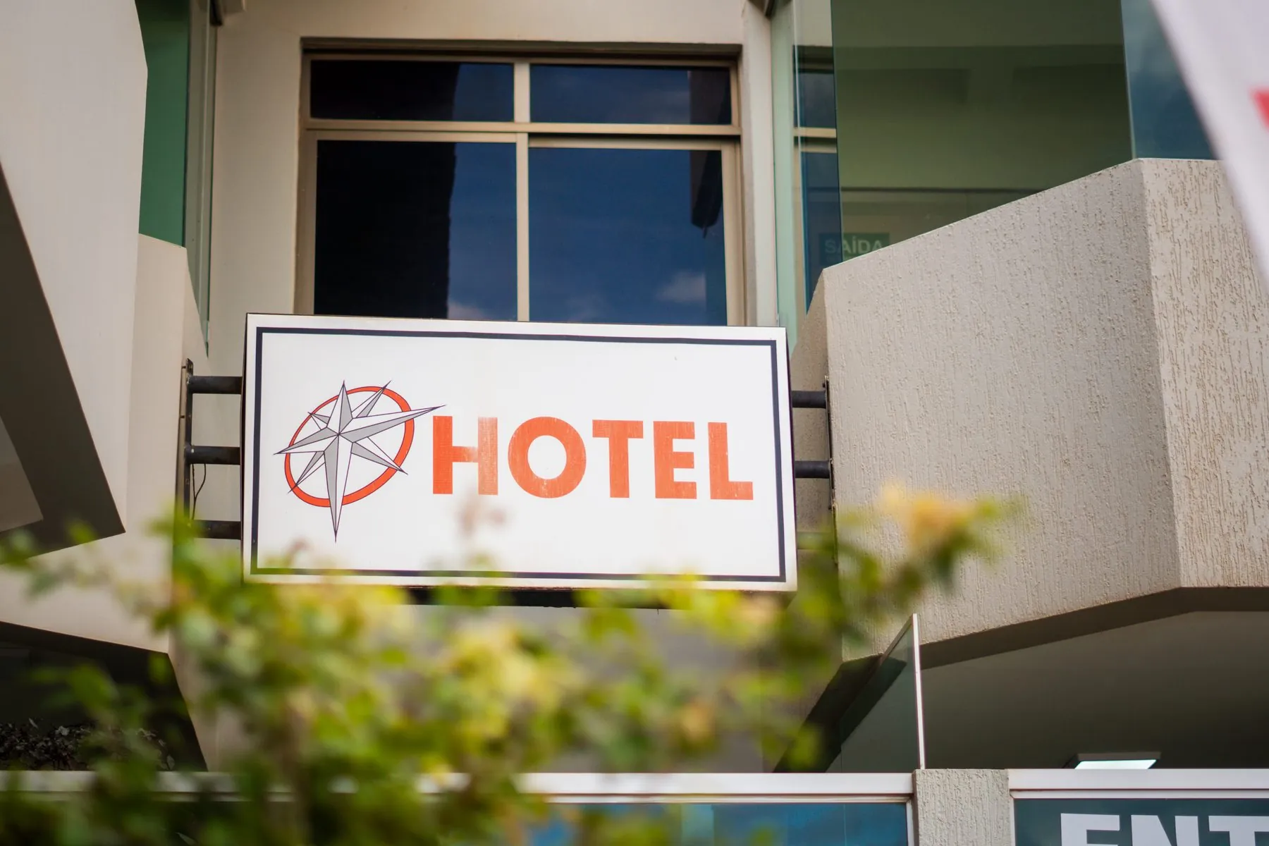 Placa do Hotel Rosário na fachada, com a rosa dos ventos, entre plantas.