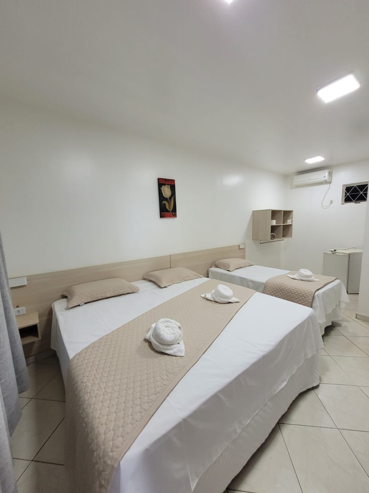 Cama de casal e solteiro no mesmo quarto, com toalhas preparadas
