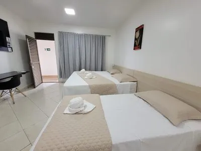 Quarto do Hotel Rosário com duas camas arrumadas e cortina cinza.