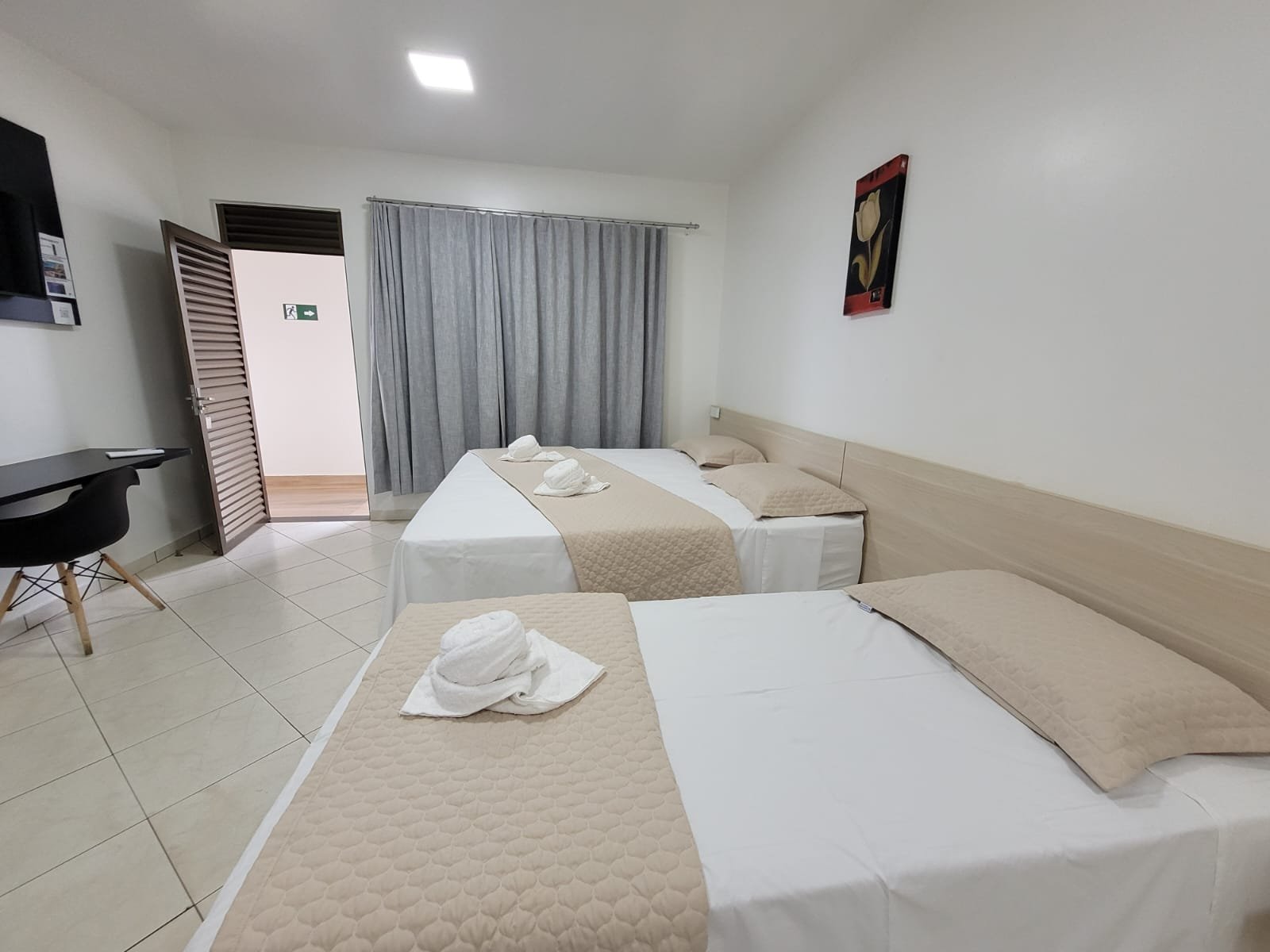 Quarto do Hotel Rosário com duas camas, mesa de trabalho e ar-condicionado