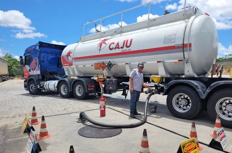 Descarga de combustível da carreta-tanque Caju, com o frentista ao lado e cones em volta.