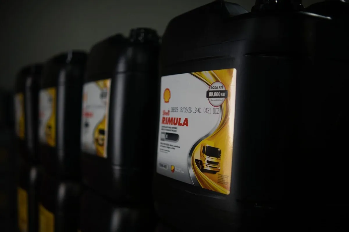 Galões pretos de Shell Rimula enfileirados, o da frente com o rótulo amarelo em foco.
