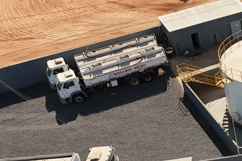 Dois caminhões-tanque Rosário Diesel estacionados no pátio da base, vistos do alto, ao lado do galpão.