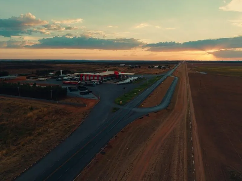 O Rosário Premium ao pôr do sol, à esquerda da rodovia que segue reta até o horizonte.