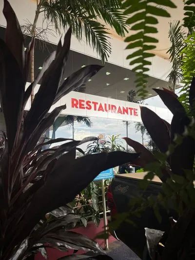 Letreiro Restaurante visto entre folhas escuras.