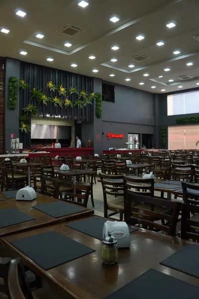 Salão do Restaurante Rosário com as mesas postas, o jardim vertical na parede e o letreiro Rosário aceso.
