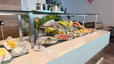 Bancada de frutas do Restaurante Santa Helena: abacaxi, banana, mamão, melancia e potes de cereais.