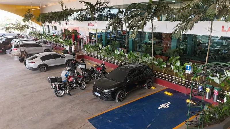 Frente do restaurante do Posto Rosário vista do alto: jardim, vaga de acessibilidade, um carro e motos de viagem estacionadas.