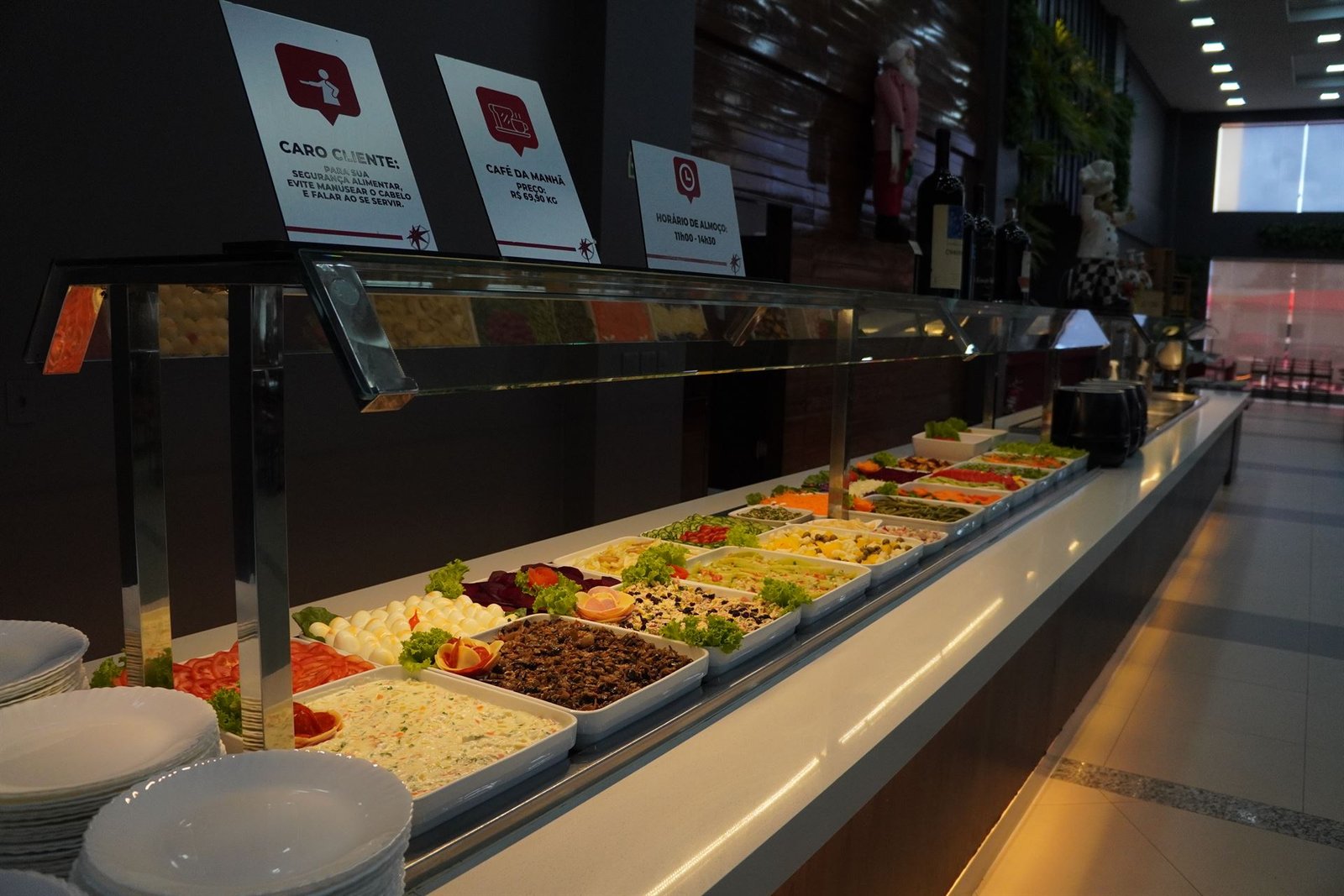 Ilha de saladas do buffet, com placas de horário e preço