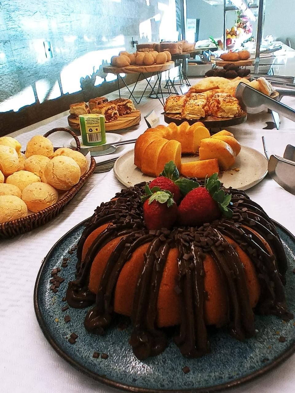 Bolo de chocolate com morangos ao lado do pão de queijo