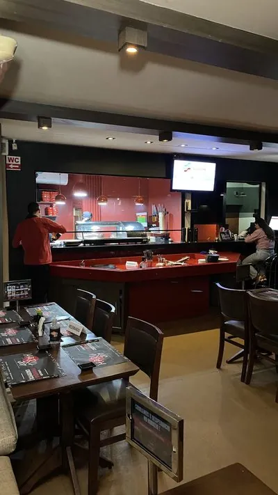 Balcão vermelho do sushi bar do Haru Joy Premium, com as mesas do salão na frente.