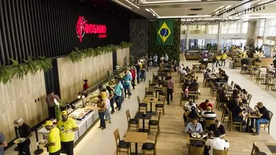 Praça de alimentação do Restaurante Premium cheia: a fila no buffet sob o letreiro Rosário Premium e as mesas ocupadas.
